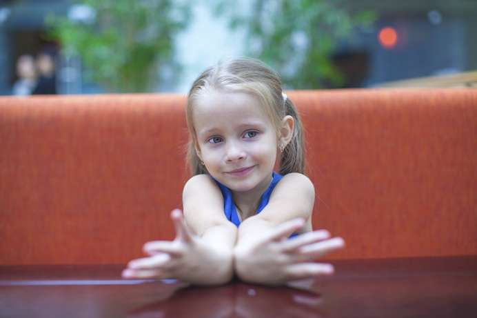 Closeup portrait of cute little girl sitting at table.